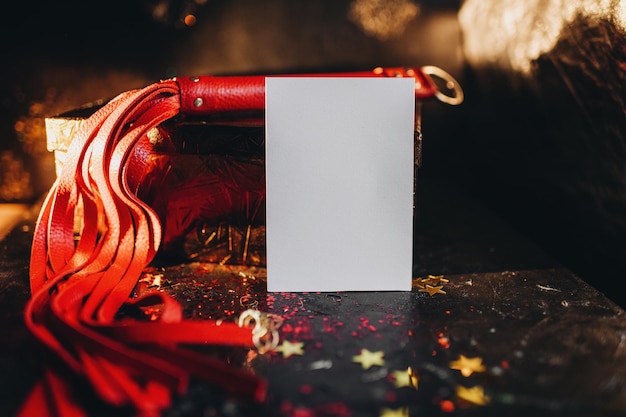 card mockup, mockup of a white sheet of paper bdsm toys, red leather whip on a black background with