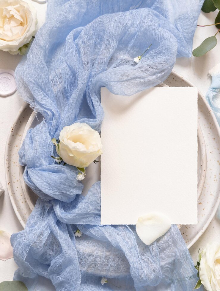 Photo カード近くの青いチュール織物の結び目とプレート上のクリームバラトップビューコピースペース結婚式のモックアップ