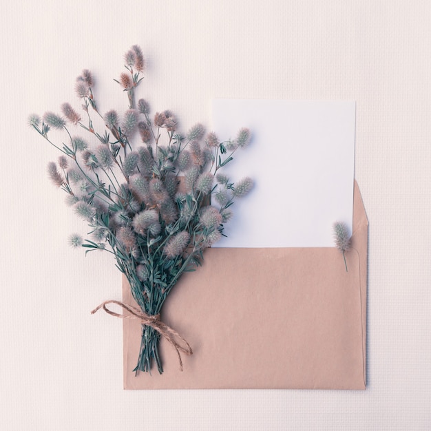 デザイン用のコピースペースが付いている封筒に野生のふわふわの花の花束が付いているカード