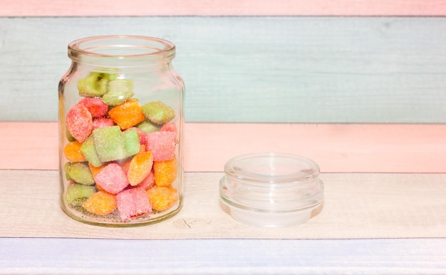 card with colorful candies in a jar on a wooden background Sweet food Food closeup