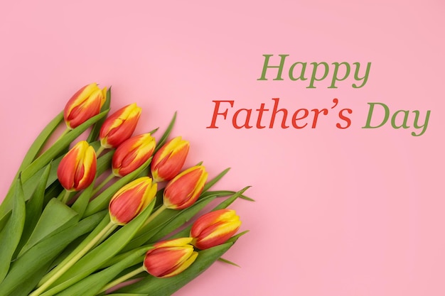 Photo card with the inscription happy fathers day with tulips on a pink backgroundholiday congratulation