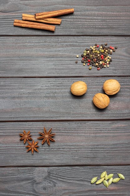 Cardamom seeds star anise walnut allspice and sticks on dark wooden background