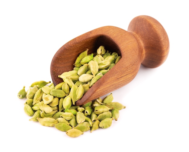 Cardamom seeds in wooden scoop, isolated on white. Pile of green cardamom pods.