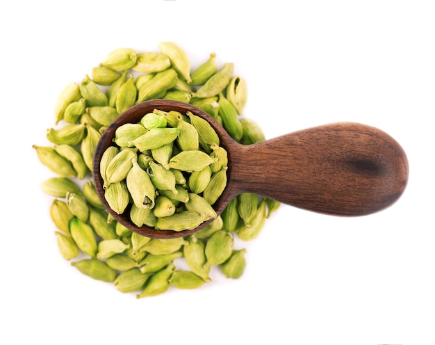 Cardamom seeds in wooden spoon, isolated on white.