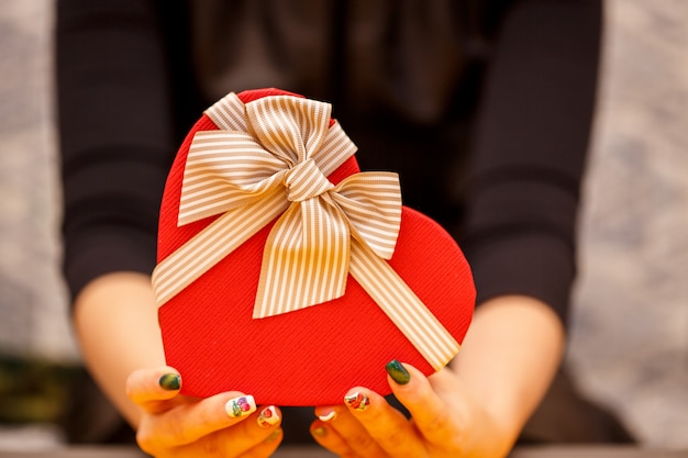 Scatola regalo biodegradabile in cartone a forma di cuore nelle mani delle donne