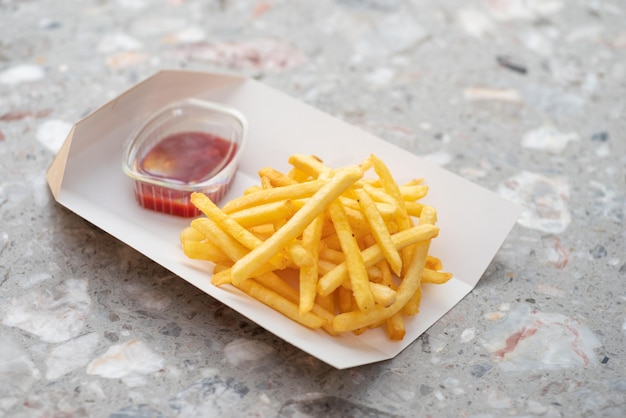 Cardboard box of French fries in a takeaway dish of a snack