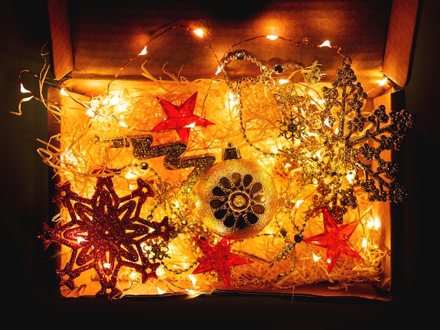 Photo cardboard box with christmas and new year decorations and light bulbs.