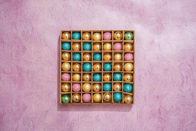 Cardboard box with many christmas spheres with pink background