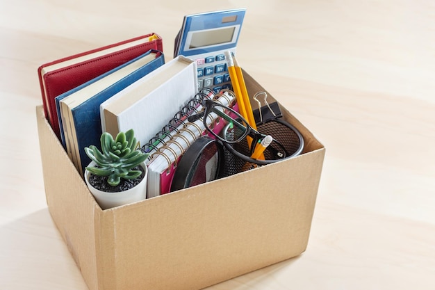 Photo cardboard box with office suplies on the desk dismissal of employment and resignation concept