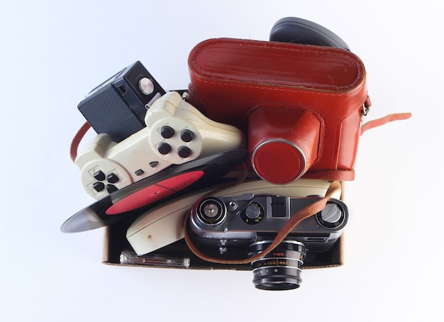 Cardboard box with retro film camera, gamepad,  vinyl record, phone tube on a white