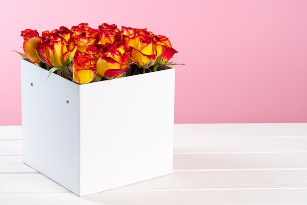 Cardboard box with roses on pink background