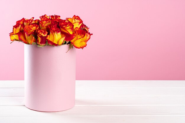 Cardboard box with roses on pink surface