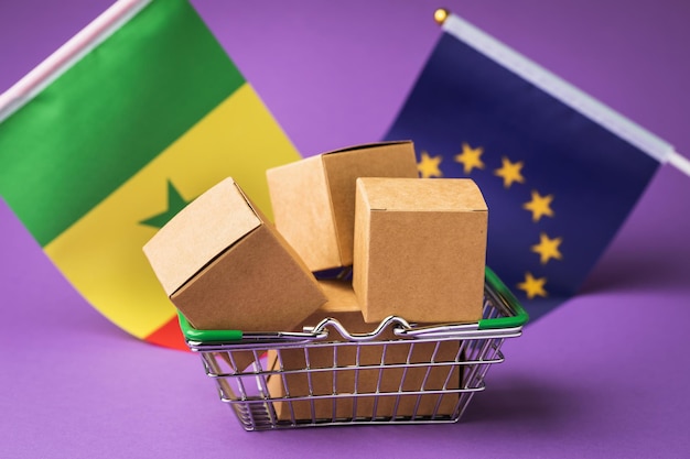 Cardboard boxes in a food basket and flags the concept of trade between the EU and Senegal