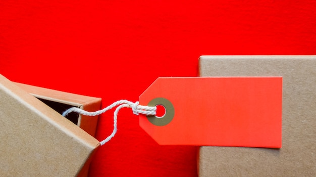 Cardboard boxes with a tag. Brown packing box with blank label and copy space on red backdrop.