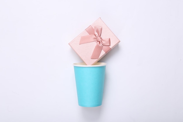 Cardboard cup with gift box on white background