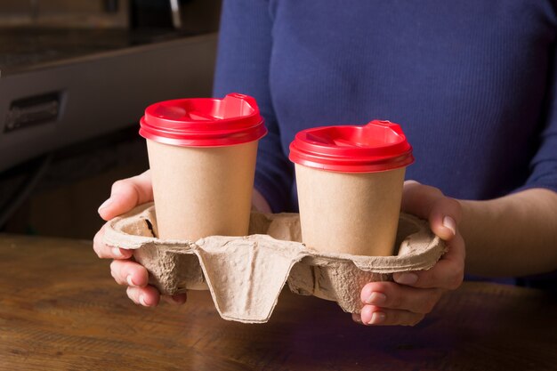 Cardboard cups with cappuccino in a takeaway stand in the hands of a woman