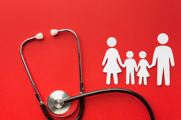 Cardboard family shapes with stethoscope on red background