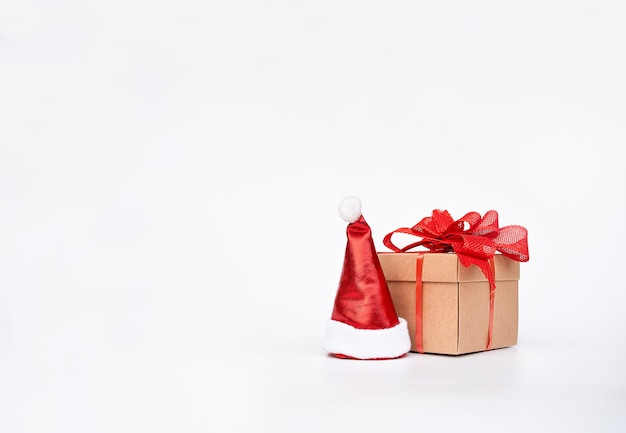 Cardboard gift box with the red bow next to the santa hat