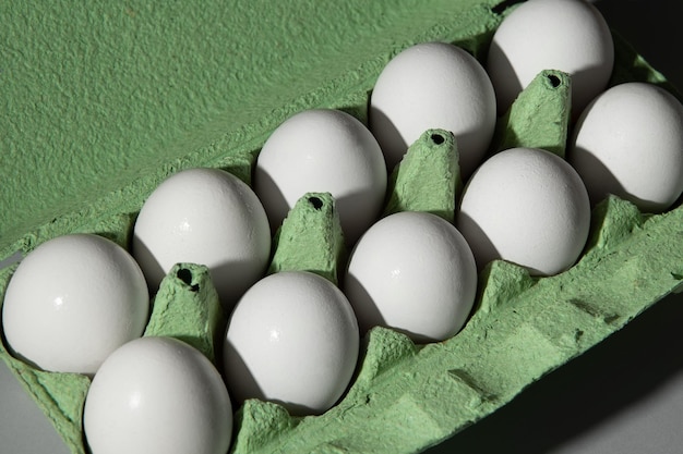 Cardboard green egg box on a gray background, a lot of eggs are in the box.