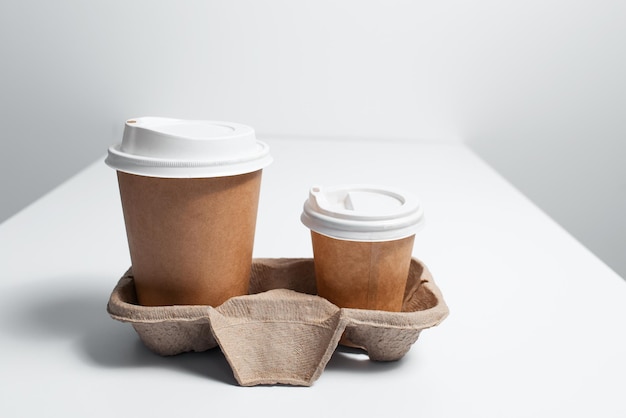 Cardboard holder with paper cups of coffee takeaway on white table