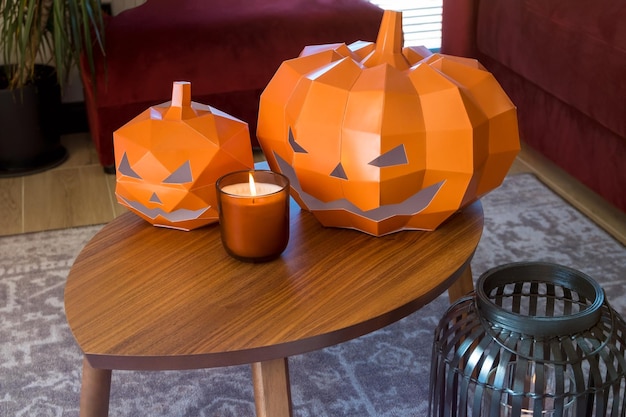 Cardboard paper orange pumpkins for Halloween. Installation with candles and fruit on the table
