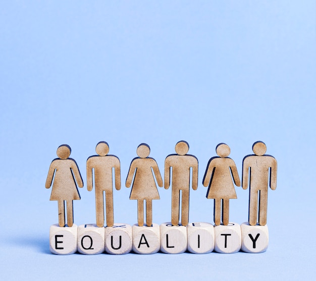 Cardboard people standing on equality word written on wooden cubes