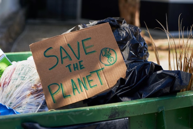 Cardboard sign written Save the planet on a pile of garbage Recycle reuse concept