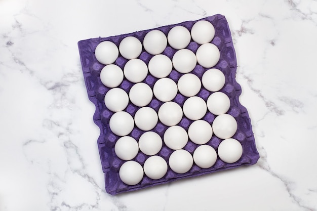 A cardboard tray of 30 eggs on a marble background