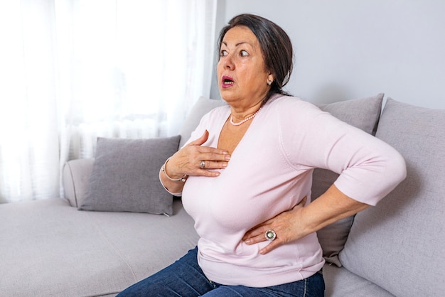 Cardiac pain. Mature woman holds her heart