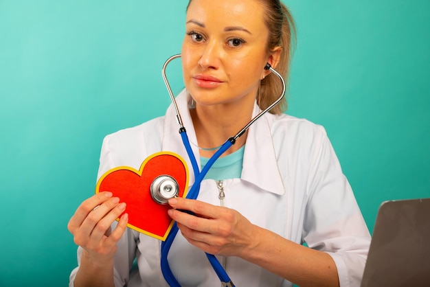 Photo cardiologist holding heart model and stethoscope in his office heart attack concept