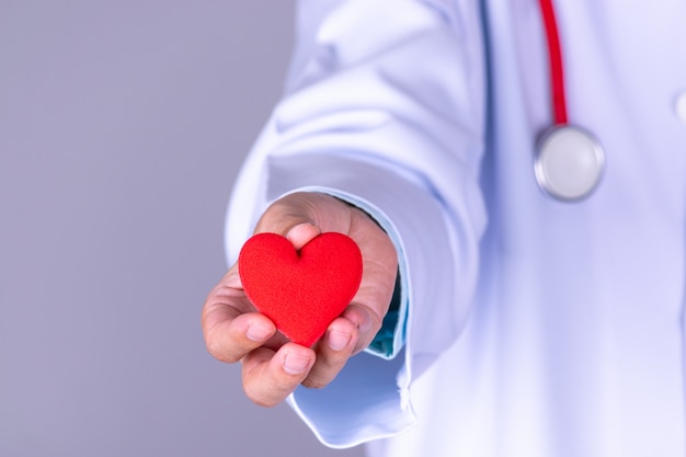 Foto cardioloog arts die rood hart in het ziekenhuis houdt