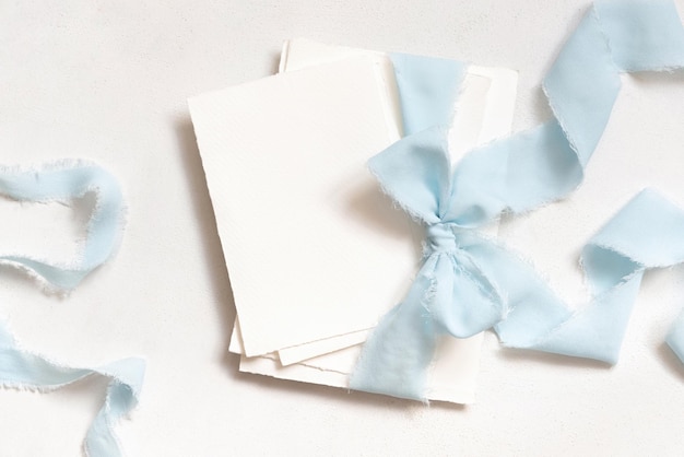 Photo cards tied with a light blue ribbons on white table top view copy space wedding stationery mockup