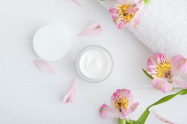 Care cream and flowers on a colored background top view skin care cosmetics