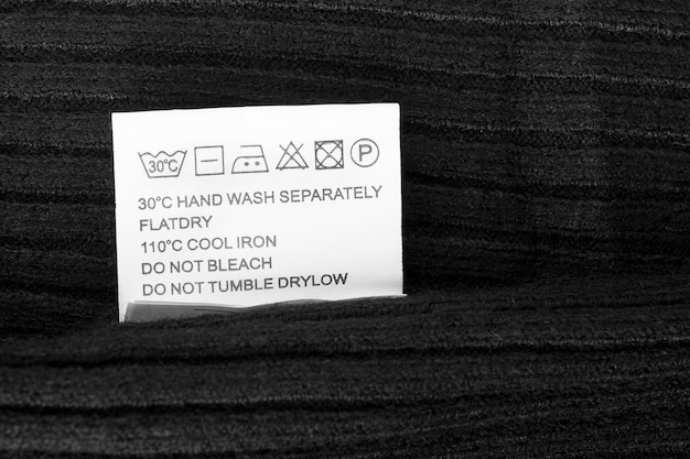 Photo care instructions clothing label on black knit background