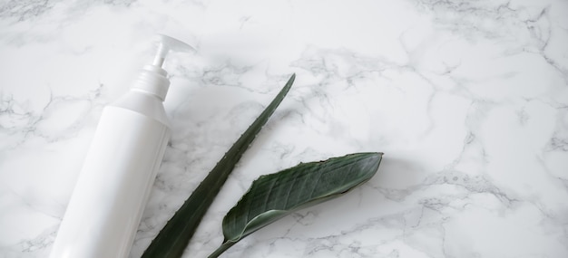 Care product and natural leaves on a marble surface