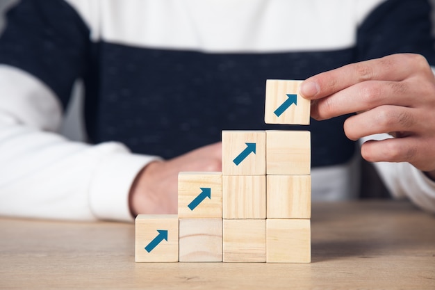 Career growth concept. Man holding wooden cubes to the top with arrows.