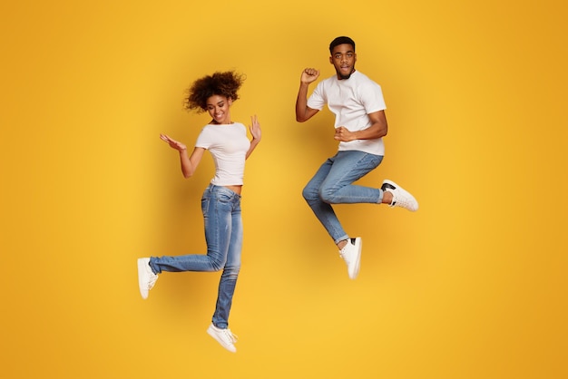 Carefree african american man and woman jumping in air