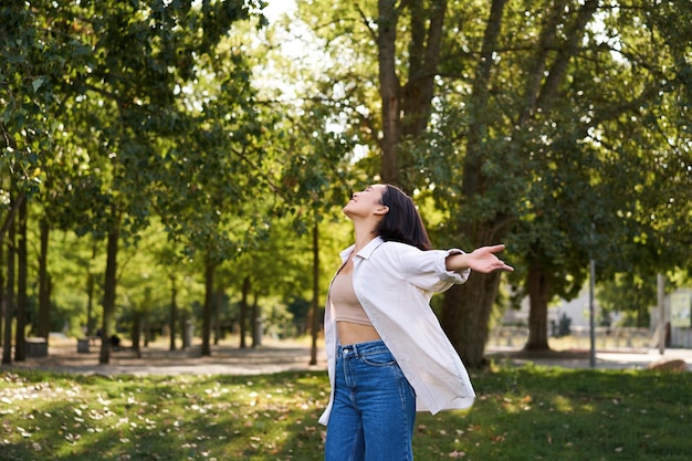 Foto ragazza asiatica spensierata che balla sentendo felicità e gioia godendosi il sole il giorno d'estate camminando nel parco