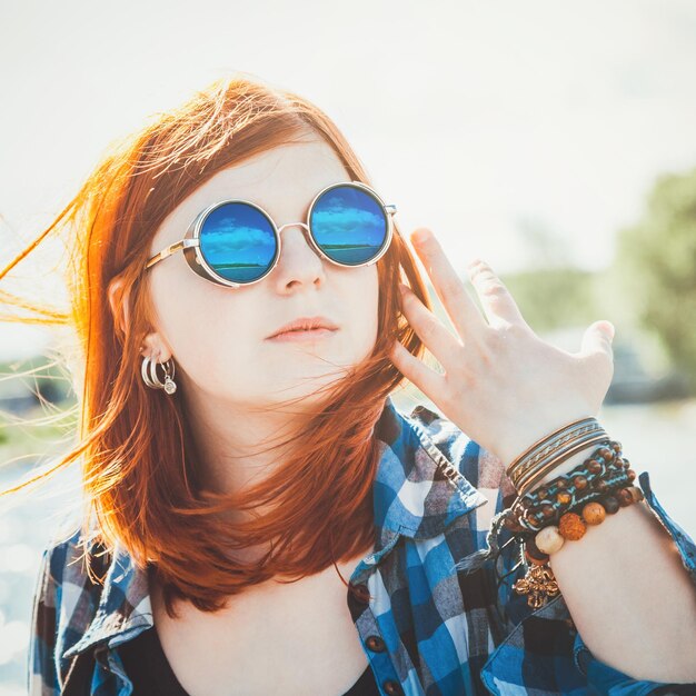 Carefree beautiful young woman in sunglasses with reflection over seascape