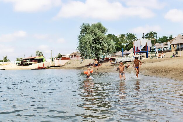 Foto ragazzi spensierati che corrono nell'acqua e si divertono sulla spiaggia durante la giornata estiva