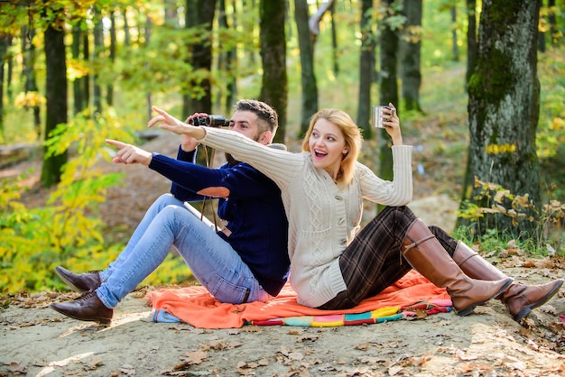 Carefree camping family picnic surprised girl drink mulled wine
bearded man shocked watch with binoculars spring mood camping and
hiking couple in love relax in autumn forest with tea or
coffee