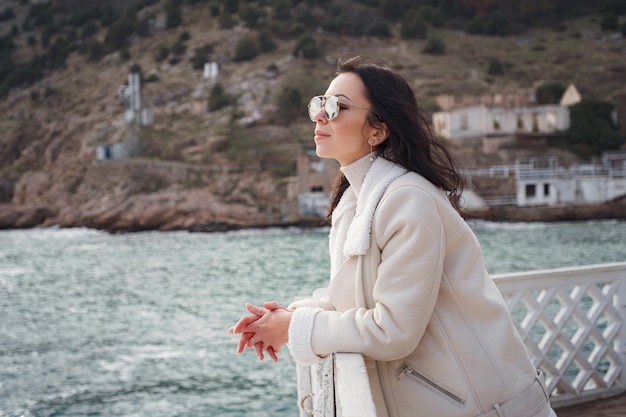 Foto donna caucasica spensierata in abiti beige che si gode la vista del mare