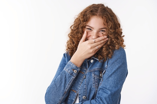 Spensierata affascinante ragazza amichevole che si diverte a scherzare ridendo ad alta voce coprire la bocca con il palmo ridacchiando su una situazione divertente, in piedi divertito allegro sfondo bianco felice di trascorrere del tempo