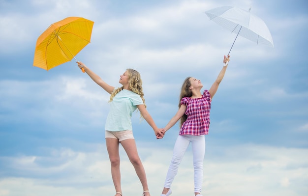 Carefree children outdoors Girls friends with umbrellas cloudy sky background Ready for any weather Windy or rainy we are prepared Freedom and freshness Weather forecast Weather changing