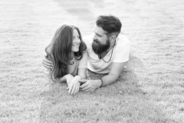 Carefree couple enjoying sunny day relaxing on green meadow love from first sight concept