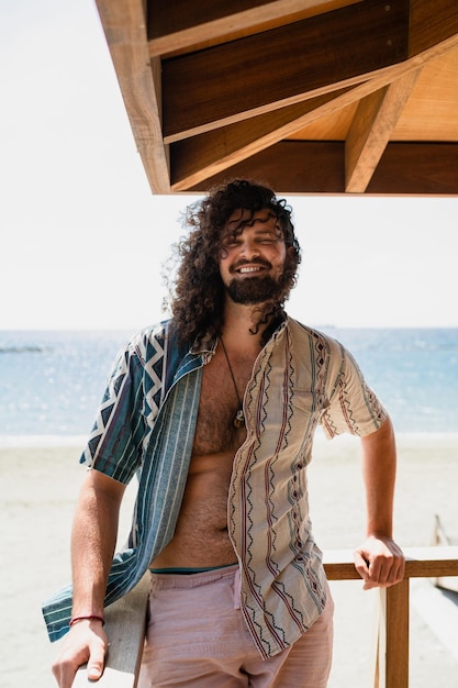 Carefree curly man relaxing on the beach during summer suny day