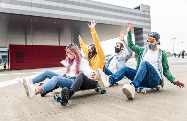 Foto amici spensierati che indossano maschere che fanno skateboard per strada