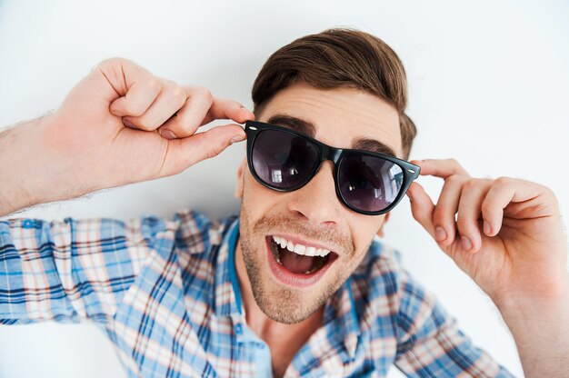 Carefree fun. Top view of cheerful young man adjusting eyewear