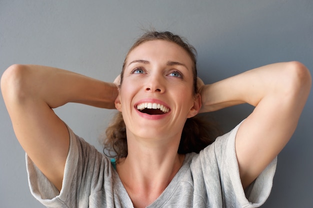 Беззаботная счастливая женщина смеется с руками в волосах