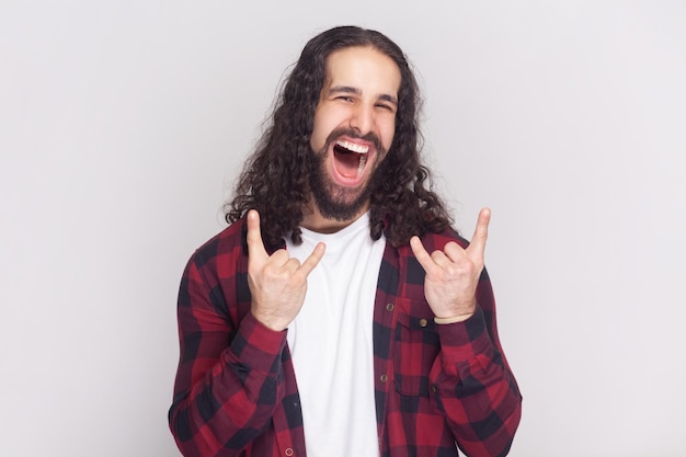 Carefree joyful man makes rock n roll gesture heavy metal sign enjoys favorite music